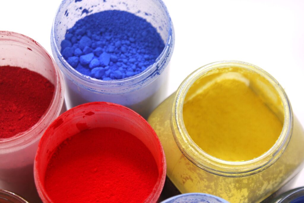 Pigmentos para pintura en polvo de colores primarios en envases industriales.